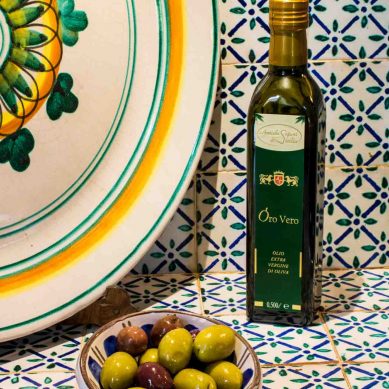 Bottiglia di Olio Extra Vergine di Oliva e Olive su Sfondo Ceramiche Siciliane