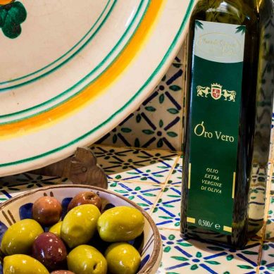 Bottiglia di Olio Extra Vergine di Oliva e Olive su Sfondo Ceramiche Siciliane